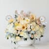 Pastel floral arrangement in a white bowl with animal picks