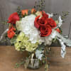 Bouquet of red and orange roses with white hydrangeas in a glass vase