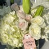 White roses and pale hydrangeas with green lily buds in a glass vase