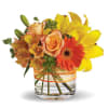 Bouquet of yellow lilies, orange roses, and a gerbera daisy in a glass vase