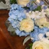 Cream roses and blue hydrangeas arranged in glass containers
