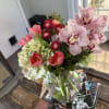 Bouquet of pink orchids, tulips, hydrangeas, and red blooms in a glass vase