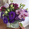 Purple bouquet with orchids, lisianthus, hydrangea, and a glass vase