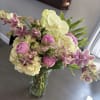 Bouquet of pink peonies, white hydrangeas, and spotted orchids in a glass vase
