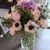 Bouquet of pale pink and purple flowers in a clear glass vase