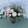 Pink and white roses arranged in a purple glass vase