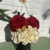 Red carnations and white roses in a black hatbox with butterfly picks