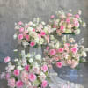 Pink and white rose arrangements with trailing fabric on clear stands