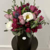 Pink and white tulip bouquet in a black hatbox with greenery