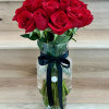 Red roses arranged in a clear glass vase with a dark ribbon