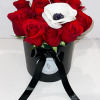 Red roses with a white anemone in a black hatbox tied with ribbon