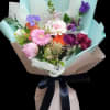 Mixed bouquet of pink, purple, white, and orange flowers wrapped in pastel paper