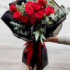 Bouquet of red roses wrapped in black paper with a red ribbon