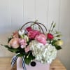 Pink and white floral arrangement in a pink gift box with ribbon handles