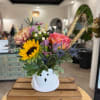 Mixed bouquet in a white ghost-shaped vase with sunflowers and roses