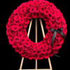 Red rose wreath on a wooden easel with a black ribbon