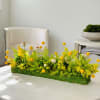 Low rectangular floral arrangement with yellow blooms on a table
