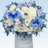 Round hatbox arrangement of cream roses, white lisianthus, blue orchids, and blue hydrangeas.