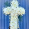 White floral cross arrangement on an easel with palm fronds