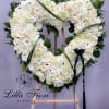 Heart-shaped floral wreath of white and blush flowers on an easel