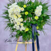 Heart-shaped floral wreath with white chrysanthemums and pale yellow roses on an easel