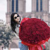 Woman holding a large bouquet of red roses in front of a cathedral