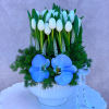 White tulips and blue orchids arranged in a white vase