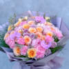 Lavender-wrapped bouquet of pink and peach roses with purple orchids