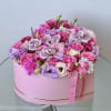 Pink and lavender floral arrangement in a round pink box with ribbon