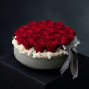 Round box of red roses with a gray ribbon on a dark background