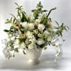 White roses and orchids arranged in a white urn vase