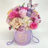 Pink and lavender flower arrangement in a lavender hat box with a butterfly topper