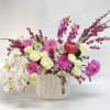 Mixed bouquet of white orchids, cream roses, pink dahlias, and purple orchids in a white vase