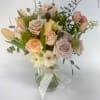 Mixed pastel roses and tulips in a clear glass vase with a ribbon