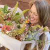 Woman holding a pastel mixed flower bouquet wrapped in white paper