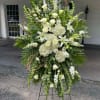 Large white floral standing spray on an easel with roses and lilies