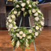 Large white floral wreath on a stand with roses and chrysanthemums