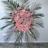 Pink floral standing spray with palm fronds on an easel