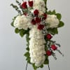 Standing cross of white flowers with red roses on an easel