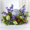Purple and blue floral arrangement around a gray urn