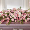 Pink roses and lilies arranged across a casket