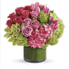 Pink roses and tulips arranged in a green glass vase