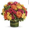 Bouquet of orange, pink, and yellow roses in a green glass vase