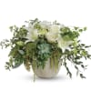 White lilies and roses in a ceramic vase with trailing greenery