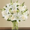 White lilies and cream roses in a clear glass vase