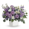 Lavender roses and white flowers in a clear square vase