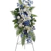 Standing floral spray with white lilies and blue flowers on an easel