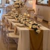 Long banquet table with white floral centerpieces and gold accents