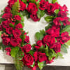 Heart-shaped arrangement of red roses with green foliage