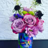 Bouquet of purple roses and mixed blooms in a colorful cat-print vase